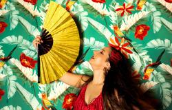 Cantora vestida de vermelho se abana com um leque e um ambiente decorado com estampa floral vermelha e verde.