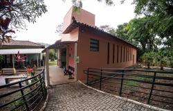 A imagem mostra a área externa de parte do equipamento cultural, revelando uma rampa de acesso pavimentada com blocos de concreto cinza e um edifício térreo pintado em tom terracota. 