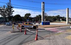 Carro da BHTrans parado em frente à Praça da Pampulha, em dia de céu azul, com área demarcada por cones