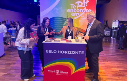 Representantes da Belotur no evento com cartazes nas cores LGBT+ ao fundo