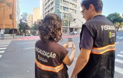 Imagem de dois fiscais da prefeitura, de costas, manuseando pelo celular a nova ferramenta de fiscalização