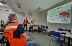 Imagem mostra homens com coletes da Defesa Svil assistindo a uma apresentação em power point.