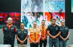 A imagem mostra seis homens perfilados em frente a várias telas que mostram mapas meteorológicos de Minas Gerais. Entre eles está o prefeito Álvaro Damião, que veste colete na cor alaranjado, na Defesa Civil de BH