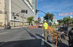 Avenida com sinalização de trânsito para corrida ao lado direito e prédios ao lado esquerdo. 