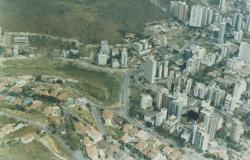 Foto aérea do Bairro Sion na década de 1990, com prédios e área verde em elevações. 