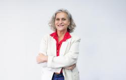 Mulher branca sorrindo, de cabelos anelados e grisalhos 