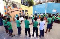 Crianças com uniforme verde fazem uma roda no pátio de uma escola da Rede Municipal de BH