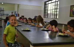 Cerca de quinze crianças merendando na cantina da escola