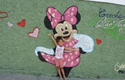 Criança em frente à nova pintura no muro da Creche São Tiago