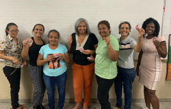 #paratodosverem: na foto, em uma sala de aula, sete mulheres estão em pé, em frente a um quadro branco, posando para a foto e sorrindo. 