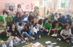 #paratodosverem: Alunos sentados em círculo no chão participam de uma atividade de leitura e conversa, com livros e cartões no centro da roda.