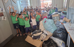 #paratodosverem: Crianças em sala de aula posam sorrindo ao lado de roupas, alimentos e brinquedos arrecadados para famílias atingidas pelas chuvas. 