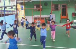 Cerca de dez crianças praticando atividades físicas na quadra da creche