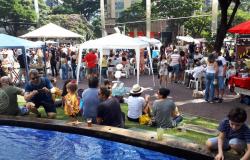 Pessoas se reúnem em uma praça com barracas de comidas e bebidas