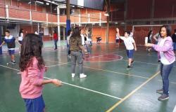 Mais de seis alunos de escola municipal jogam peteca em quadra poliesportiva. 