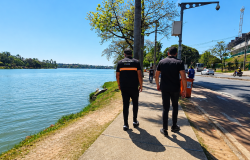 Agentes de fiscalização caminhando pela orla da Lagoa da Pampulha, em Belo Horizonte, em um dia ensolarado