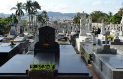 Vários túmulos do Cemitério do Bonfim durante o dia; ao fundo, árvores, a cidade e montanhas. 