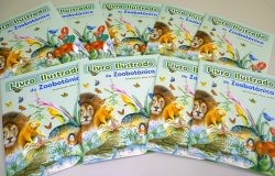 Nove livros idênticos, ilustrados, da Fundação Zoobotânica, com orientações para visitas, espalhados sobre uma mesa. 