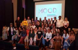 Mais de trinta pessoas, participantes da equipe do MOOd, posam para foto à frente de projeção com a logo do projeto. 