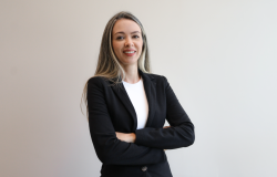Mulher com cabelo longo e loiro, pele clara, usa camisa branca e blazer preto;