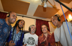 Cinco homens, em estúdio, cantando.