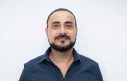 Homem branco de barba e cabelos escuros vestindo camisa azul escura de manga longa
