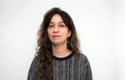 Paula Senna, Diretora de Promoção das Artes Mulher branca de cabelos longos castanhos e ondulados vestindo blusa cinza listrada