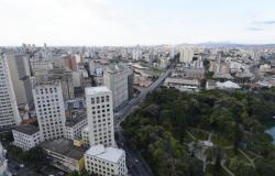 Vista aérea da cidade de Belo Horizonte, com prédios e o Parque Municipal ao fundo. 