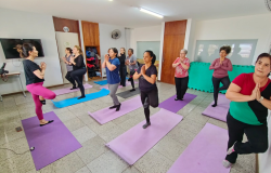 Onze mulheres em uma sala com tapetes coloridos em pé fazendo aula de yoga. 