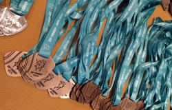 Medalhas da Olimpíada Brasileira de Matemática, com cordão azul claro, dispostas em uma mesa