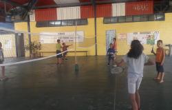 Três crianças de um lado da quadra, jogando badminton.