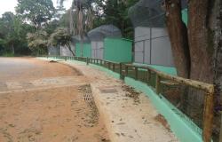 Três recintos com grade, pintados, com passeio, no Zoológico, durante o dia. 