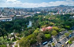 Vista aérea do Parque Municipal. No entorno, avenida e automóveis e ao fundo, edifícios e o contorno de montanhas.