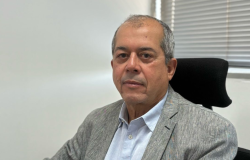 Homem de terno cinza e camisa azul posa para foto