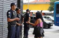 TRês guardas civis municipais conversam com cidadã, no centro de BH, durante o dia. 