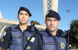 Guarda municipal mulher e guarda municipal homem, lado a lado, em frente a igrejinha da pampulha