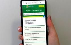 Mão segurando um celular com a tela do novo Portal de Serviços da Prefeitura
