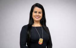Mulher branca sorrindo, de cabelo preto, liso e longo.