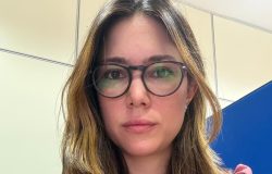 Mulher branca, usando óculos de grau, cabelos escuros com mechas loiras