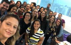 Cerca de vinte mulheres e uns três homens de uma das edições do curso Programando Sonhos Delas posam para foto do tipo selfie, em uma sala. 