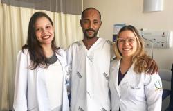 Duas doutoras e um paciente abraçados e sorrindo em quarto de hospital