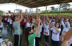 Dezenas de pessoas com as mãos pra cima praticando Lian Gong