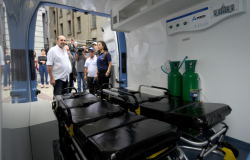 Prefeito Alexandre Kalil, com imprensa ao fundo observa interior de ambulância doada para a saúde de BH. 