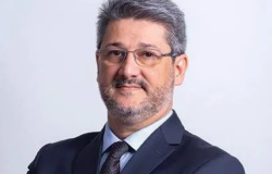 Homem de cabelo e barba grisalhos, pele clara e usa óculos.