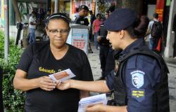 Guarda municipal feminina entrega folheto educativo sobre assédio a cidadã. Foto ilustrativa.