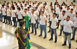 Homem segura a bandeira do Brasil na frente de centenas de jovens