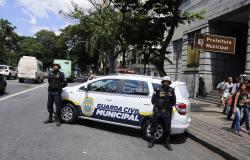 Dois guardas municipalis e um carro em frente a Prefeitura Municipal de Belo Horizonte. 