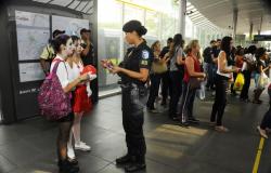 Guarda municipal feminina aborda duas pessoas, vestidas de palhaço, em estação MOVE. 