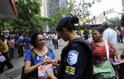 Guarda municipal feminina aborda cidadã na Praça Sete com material informativo. Foto ilustrativa.