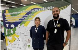 Débora Giordana, gerente de Promoção Turística da Belotur, e Márcio Ribeiro, gerente de Inovação Turística da Belotur, posam para foto durante o Seminário Internacional de Pesquisa em Políticas Públicas de Turismo, realizado em Viçosa. Ao fundo, banner apresenta a programação do evento.